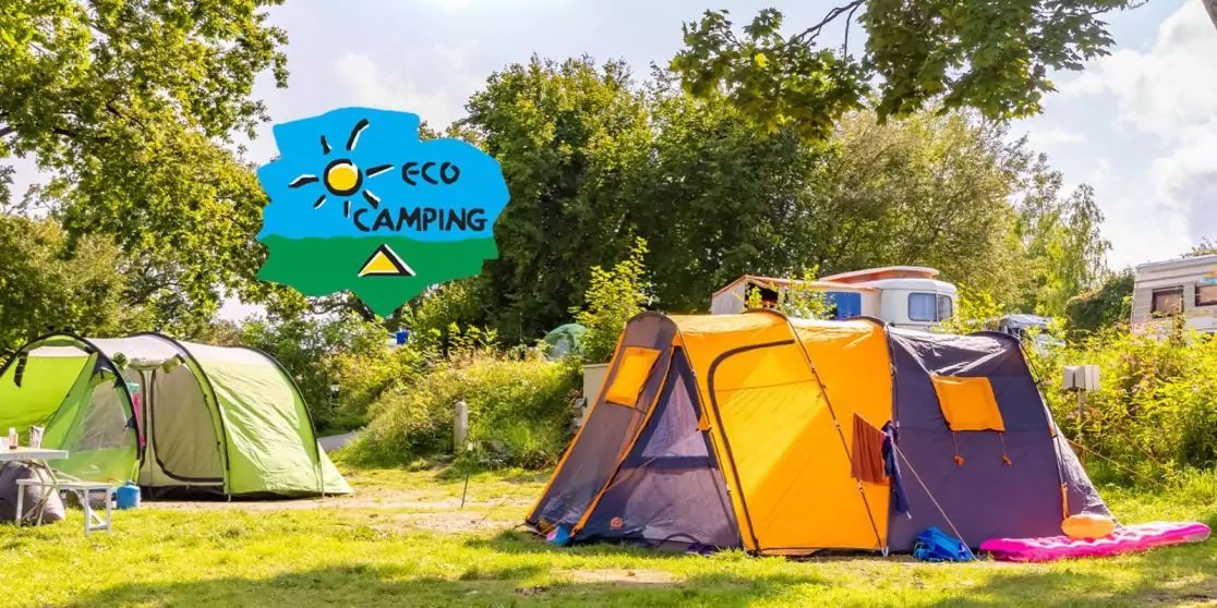 Ein orangefarbenes und ein gr&uuml;nes Zelt auf einer Wiese, B&auml;ume und Wohnwagen im Hintergrund, Schild mit der Aufschrift ECO CAMPING