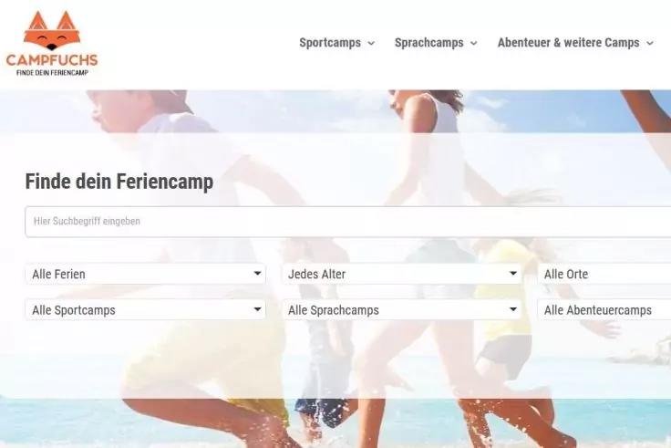 Website-Screenshot: Campfuchs-Logo oben links, Navigationsleiste, &Uuml;berschrift &laquo;Finde dein Feriencamp&raquo;, Suchfeld und mehrere Filter-Dropdowns; Hintergrundbild zeigt zwei Personen, die im flachen Meer rennen und Wasser spritzen, Himmel im Hintergrund