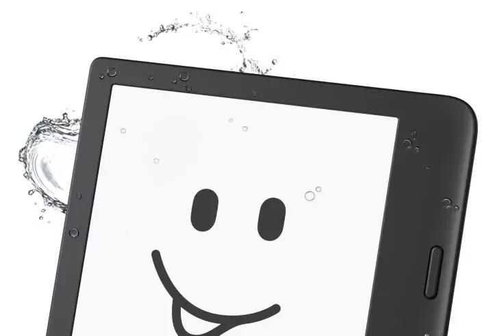 Schwarzes Tablet mit wei&szlig;em Bildschirm; zwei ovale Augen und ein Mund mit herausgestreckter Zunge auf dem Display; Wassertropfen und Spritzer am Ger&auml;t