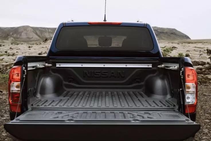 Offene Ladefl&auml;che eines schwarzen Nissan Pick-up mit ge&ouml;ffneter Heckklappe, leer, sandige H&uuml;gel im Hintergrund