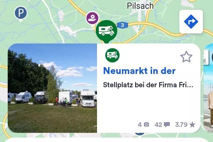 Kartenausschnitt mit &uuml;berlagerter Infokarte 'Neumarkt in der' und Thumbnail: Grasfeld mit mehreren Wohnmobilen, B&auml;ume links, blauer Himmel mit Wolken, Park-Icon 'P' oben links