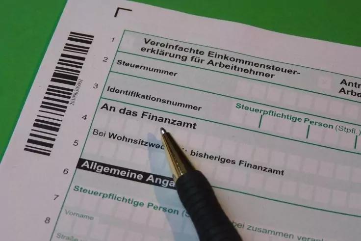 Nahaufnahme eines deutschen Steuerformulars mit der &Uuml;berschrift Vereinfachte Einkommensteuererkl&auml;rung f&uuml;r Arbeitnehmer, Feldern wie Steuernummer und Identifikationsnummer, einem Barcode links und einem schwarzen Stift, der auf ein Feld zeigt, auf gr&uuml;