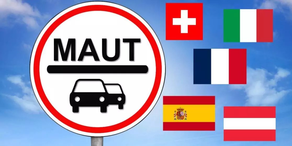 Rundes Verkehrsschild mit rotem Rand, wei&szlig;er Fl&auml;che, der Aufschrift "MAUT" und zwei schwarzen Auto-Piktogrammen auf einem Pfosten; blauer Himmel mit Wolken; rechts f&uuml;nf nationale Flaggen: Schweiz, Italien, Frankreich, Spanien, &Ouml;sterreich