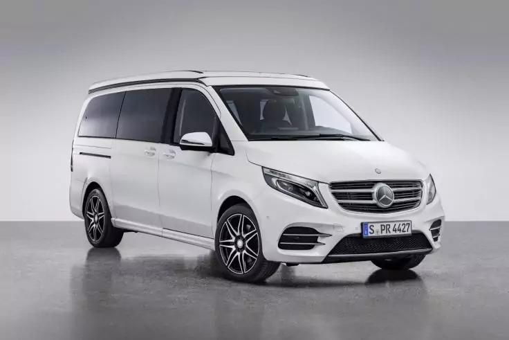 Weißer Mercedes‑Van in einem Fotostudio, front-seitliche Ansicht auf glänzendem Boden, sichtbares Markenemblem am Kühlergrill