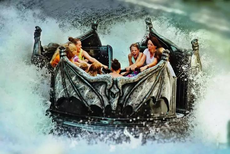 Mehrere Personen in einem runden Wasserboot mit dekorativem Drachenschmuck, umgeben von spritzendem Wasser