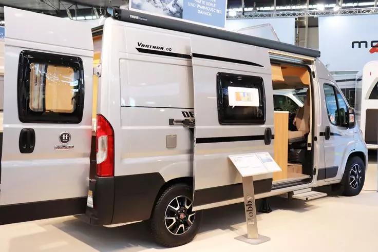 Wei&szlig;er Wohnmobil-Kastenwagen mit ge&ouml;ffneter Schiebet&uuml;r, sichtbarem Innenraum, seitlichem Fenster und Informationsst&auml;nder