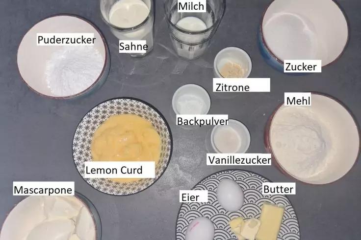 Mehrere Sch&uuml;sseln und Teller mit beschrifteten Backzutaten: Puderzucker, Sahne, Milch, Zucker, Mehl, Zitronenscheibe, Lemon Curd, Backpulver, Vanillezucker, Mascarpone, Eier, Butter