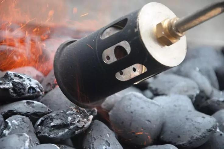 Metallbrennerd&uuml;se &uuml;ber gl&uuml;henden Kohlebriketts, sichtbare Funken und Flammen