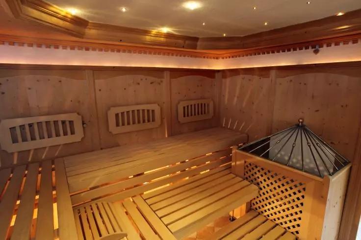 Holzraum mit gestaffelten Holzb&auml;nken, Metallofen mit Schutzgitter und Deckenbeleuchtung