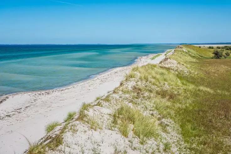 Sanddüne mit Gras, weißer Sandstrand, türkisfarbenes Meer und klarer blauer Himmel