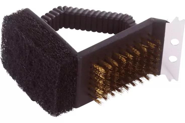 Schwarzer, gebogener Kunststoffgriff mit geriffelter Oberfl&auml;che; mittig Block mit Messingborsten; links schwarzes Scheuermaterial; rechts Metallplatte mit zwei runden L&ouml;chern. Wei&szlig;er Hintergrund