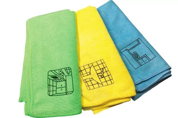 Drei gefaltete T&uuml;cher in Gr&uuml;n, Gelb und Blau mit schwarzen Symbolen, nebeneinander auf wei&szlig;em Hintergrund