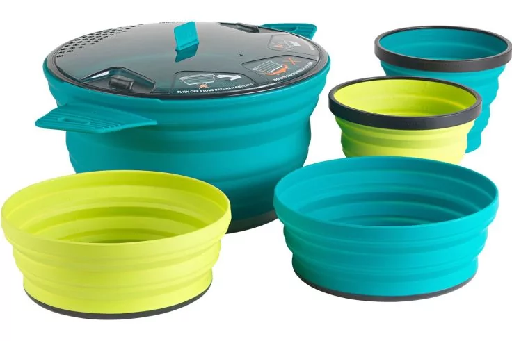 T&uuml;rkis- und limonengr&uuml;ne faltbare Silikonsch&uuml;sseln in verschiedenen Gr&ouml;&szlig;en und ein faltbarer Topf mit Griffen und Deckel auf wei&szlig;em Hintergrund