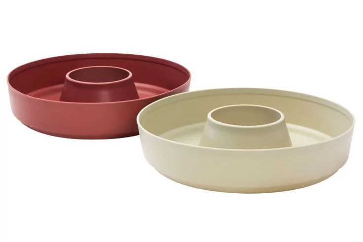 Zwei runde Formen mit mittiger R&ouml;hre, eine cremefarben vorne, eine rot hinten, auf wei&szlig;em Hintergrund