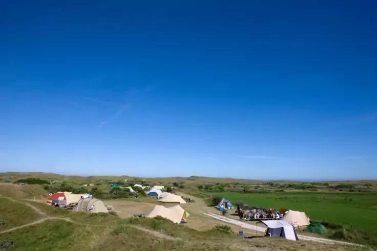 Zelte auf grasbewachsenen D&uuml;nen unter blauem Himmel