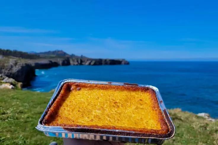 Aluminiumform mit goldbrauner Oberfl&auml;che im Vordergrund; im Hintergrund Gras, Klippen und blaues Meer unter klarem Himmel