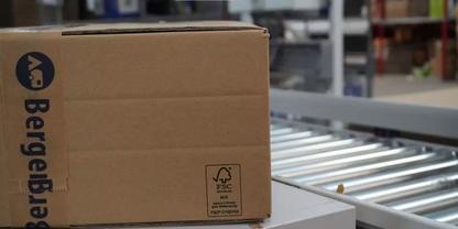 Brauner Karton mit Logo auf einem Rollenf&ouml;rderer in einem Lager