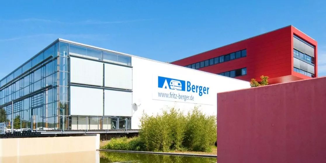 Au&szlig;enaufnahme: wei&szlig;es Geb&auml;ude mit Glasfassade und Schriftzug 'Berger', rotes Geb&auml;ude im Hintergrund, Gr&auml;ser am Wasserbecken, blauer Himmel