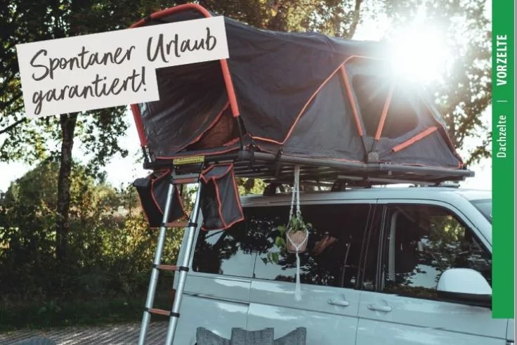 Wei&szlig;es Fahrzeug mit ge&ouml;ffnetem Dachzelt, Leiter am Fahrzeug, h&auml;ngender Blumentopf, Schild mit Text 'Spontaner Urlaub garantiert!', B&auml;ume im Hintergrund und Sonnenlicht