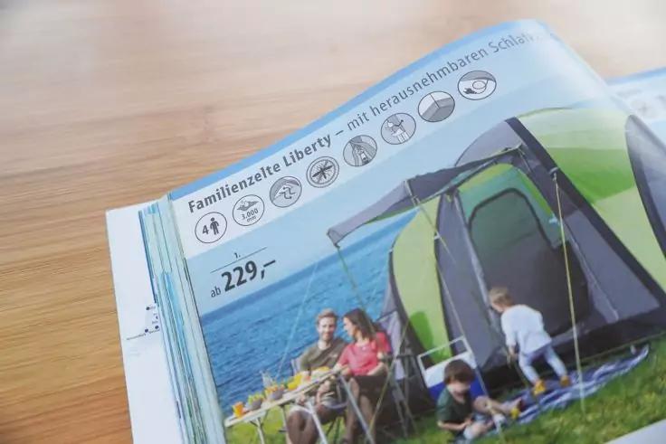 Fotografie einer Katalogseite mit gr&uuml;nem Zelt am Wasser, zwei sitzende Erwachsene, zwei Kinder, sichtbarer Preis '229,-' und Titel 'Familienzelt Liberty'