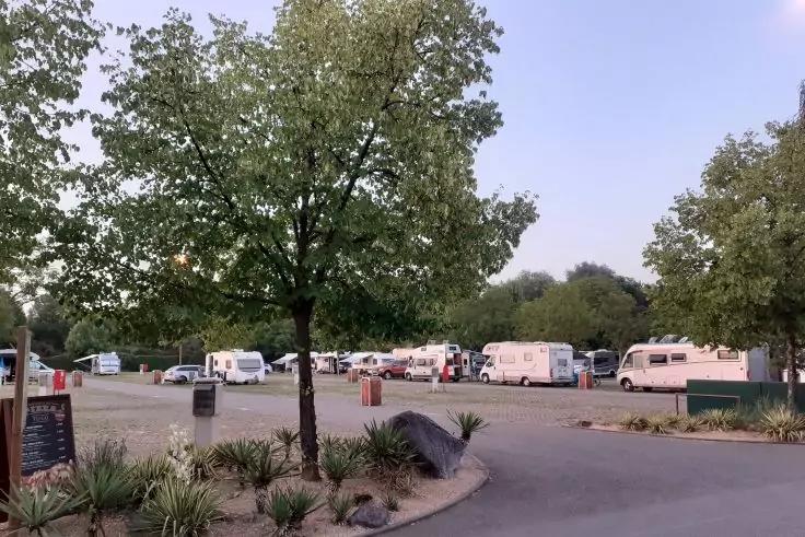 Parkplatz mit mehreren Wohnmobilen, B&auml;umen, Bepflanzungen und Fahrweg