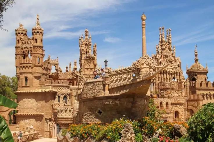 Gro&szlig;es sandfarbenes, kunstvoll ornamentiertes Steingeb&auml;ude mit T&uuml;rmen und Skulpturen, blauer Himmel, Pflanzen im Vordergrund