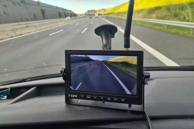 Monitor auf dem Armaturenbrett, darauf ein Bild einer Autobahn mit Fahrspuren, Leitplanke rechts und Betonschutzwand links