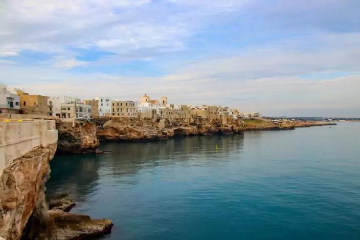 Wei&szlig;e H&auml;user auf Felsklippen am ruhigen Meer, leicht bew&ouml;lkter Himmel