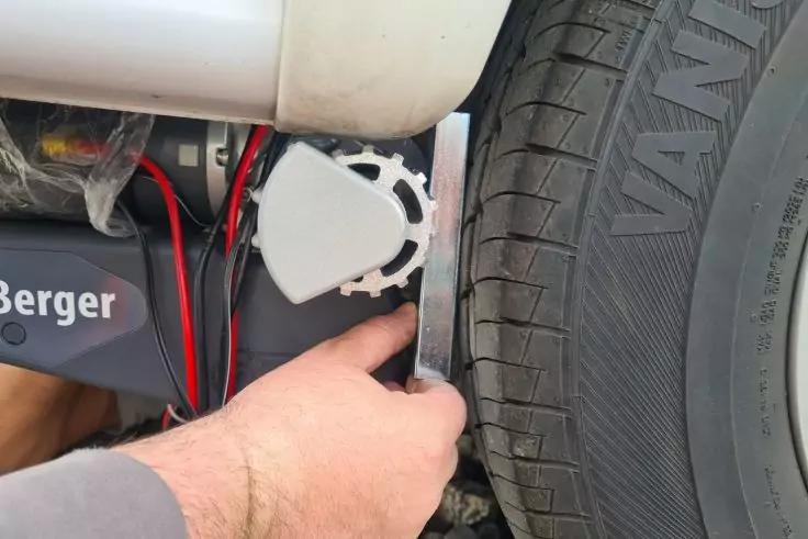 Hand h&auml;lt Metallwinkel neben Reifen; Reifenseitenwand und Profil sichtbar, rote und schwarze Kabel, wei&szlig;es Kunststoffgeh&auml;use und Geh&auml;use mit Aufdruck "Berger"