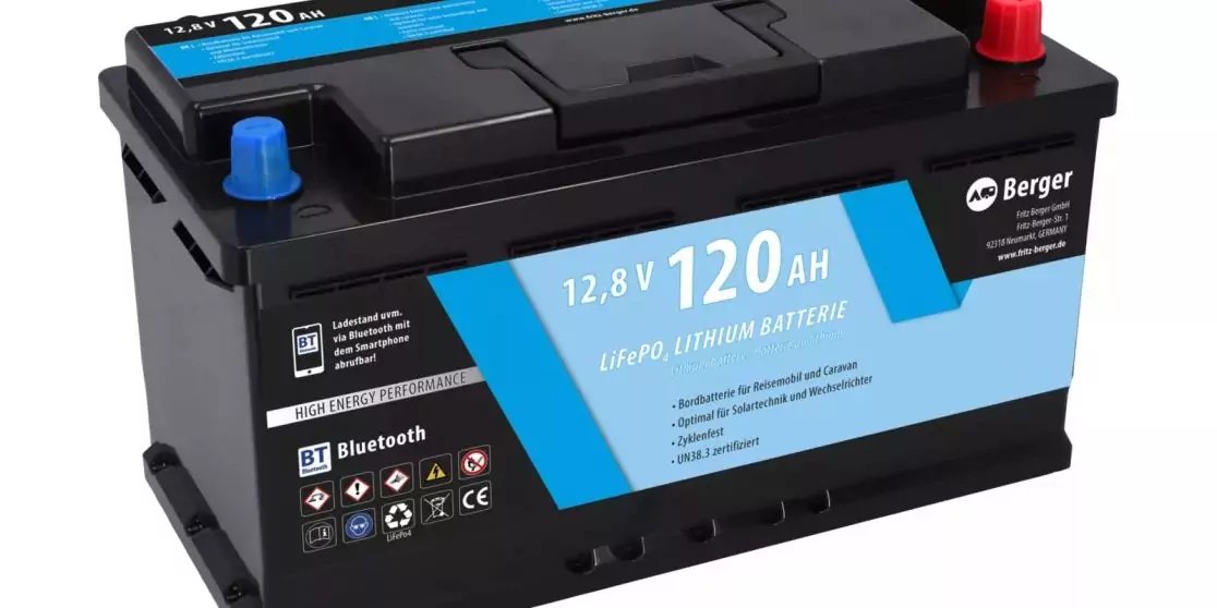 Schwarze rechteckige Batterie mit blauem Etikett '12,8 V 120 AH', zwei Anschlusskappen oben (rot und blau), Markenlogo und Piktogramme auf dem Etikett