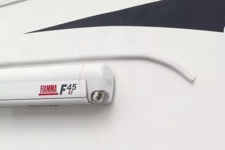 Weiße Wand mit weißem Gehäuse beschriftet "FIAMMA F45" und gebogener Metallstange