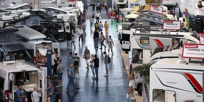 Innenhalle mit Reihen von Wohnmobilen und Menschen, die zwischen ihnen gehen