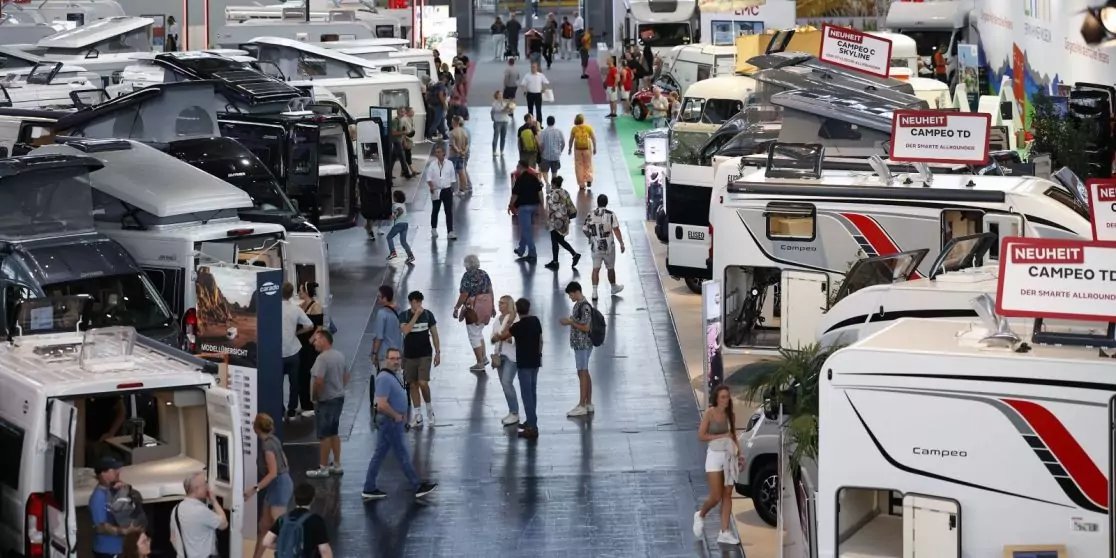 Innenhalle mit Reihen von Wohnmobilen und Menschen, die zwischen ihnen gehen