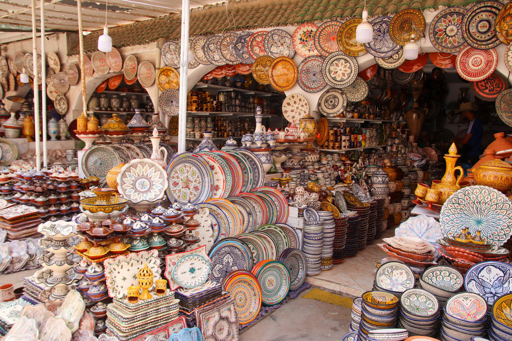 Viele bemalte Keramikteller, Schalen und T&ouml;pfe, gestapelt und in Regalen, einige Teller an der R&uuml;ckwand aufgeh&auml;ngt