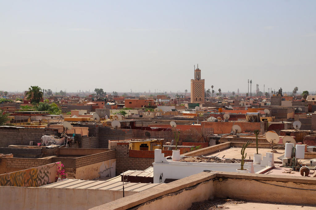 Blick auf Stadtd&auml;cher mit Terrassen, Satellitensch&uuml;sseln und einem hohen Turm unter klarem Himmel