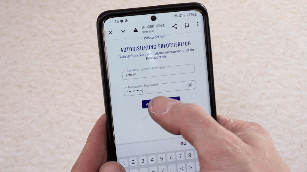 Hand h&auml;lt Smartphone, auf dem Bildschirm ein Formular mit der &Uuml;berschrift 'AUTORISIERUNG ERFORDERLICH', ein Finger tippt auf einen blauen Button