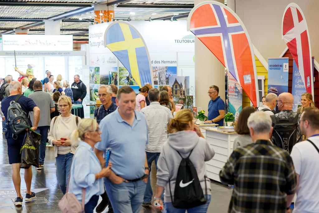 Innenraum mit Ständen und mehreren Personen; große schwedische, norwegische und dänische Flaggen sichtbar