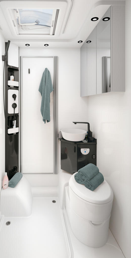 Wei&szlig;es Badezimmer mit Dachfenster, Duschbereich links mit schwarzem Duschpaneel, T&uuml;r mit aufgeh&auml;ngtem Handtuch, Waschbecken mit schwarzer Armatur und Spiegelschrank, Toilette mit gefalteten Handt&uuml;chern