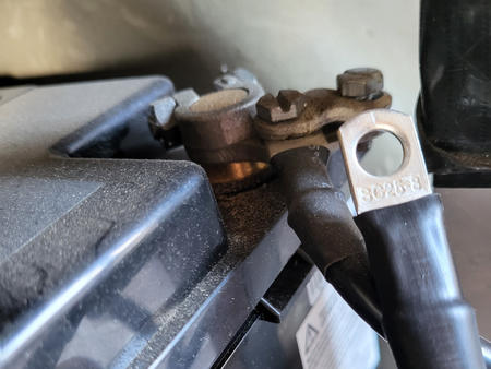 Nahaufnahme eines Batteriepols mit angeschraubtem Ringkabelschuh und schwarzem Kabel an einem Plastikbatteriegeh&auml;use