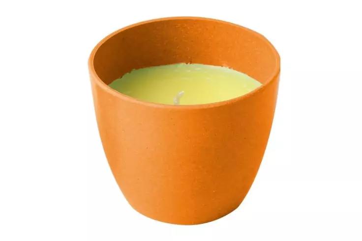 Récipient orange avec cire de bougie verte et une mèche sur fond blanc