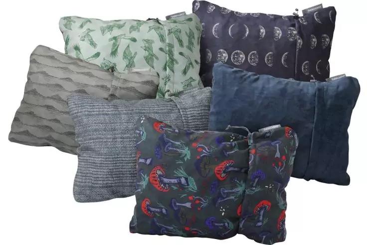 Sept coussins : deux foncés à l'avant avec motif d'oiseaux colorés ; au centre un gris à fines rayures et un bleu texturé ; à l'arrière un gris clair ondulé, un vert à motif de feuilles et un bleu foncé à motif de phases lunaires