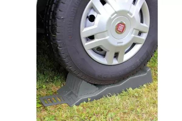 Gomma di automobile con copricerchio e logo Fiat su una rampa di plastica grigia su erba