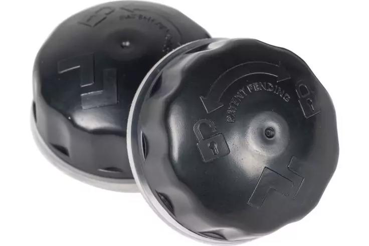 Due tappi di plastica neri e rotondi con frecce in rilievo e simboli di blocco su sfondo bianco