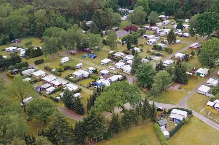 Veduta aerea di numerose roulotte e piccole casette su lotti erbosi tra alberi e strade strette