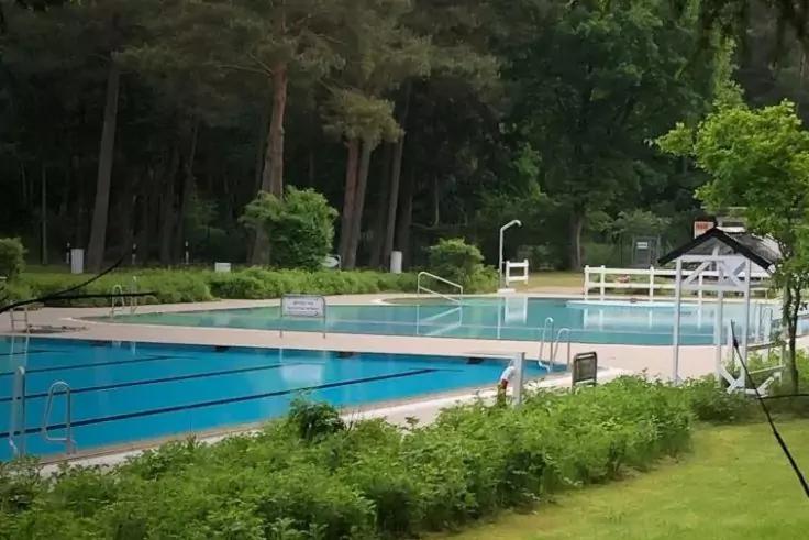 Piscina all'aperto con corsie di nuoto, acqua, bordo piscina e alberi sullo sfondo