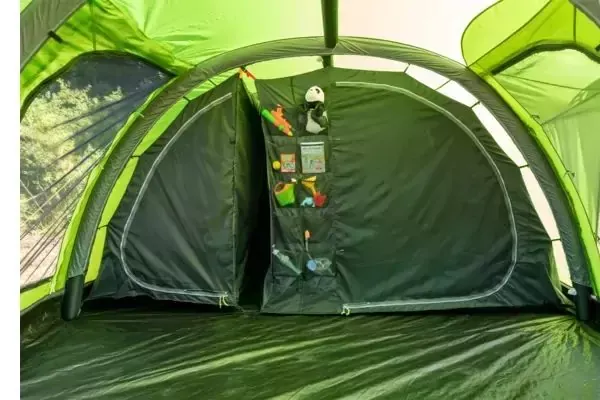 Interno di una tenda verde con un organizer appeso al centro con tasche e oggetti