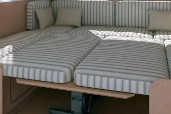 Due cuscini a righe affiancati su una struttura in legno, due cuscini per lo schienale, luce da una finestra