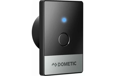Dispositivo rettangolare nero con un pulsante rotondo al centro, un LED blu sopra e una striscia argento in basso con la scritta 'DOMETIC'