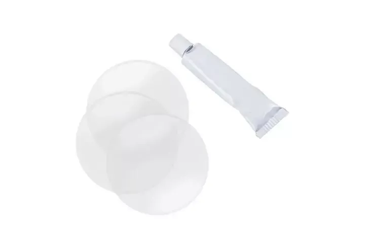 Due dischi rotondi, sottili e bianchi traslucidi accanto a un piccolo tubo bianco con tappo a vite