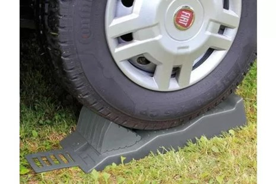 Autoband op een grijs plastic oprijblok op gras